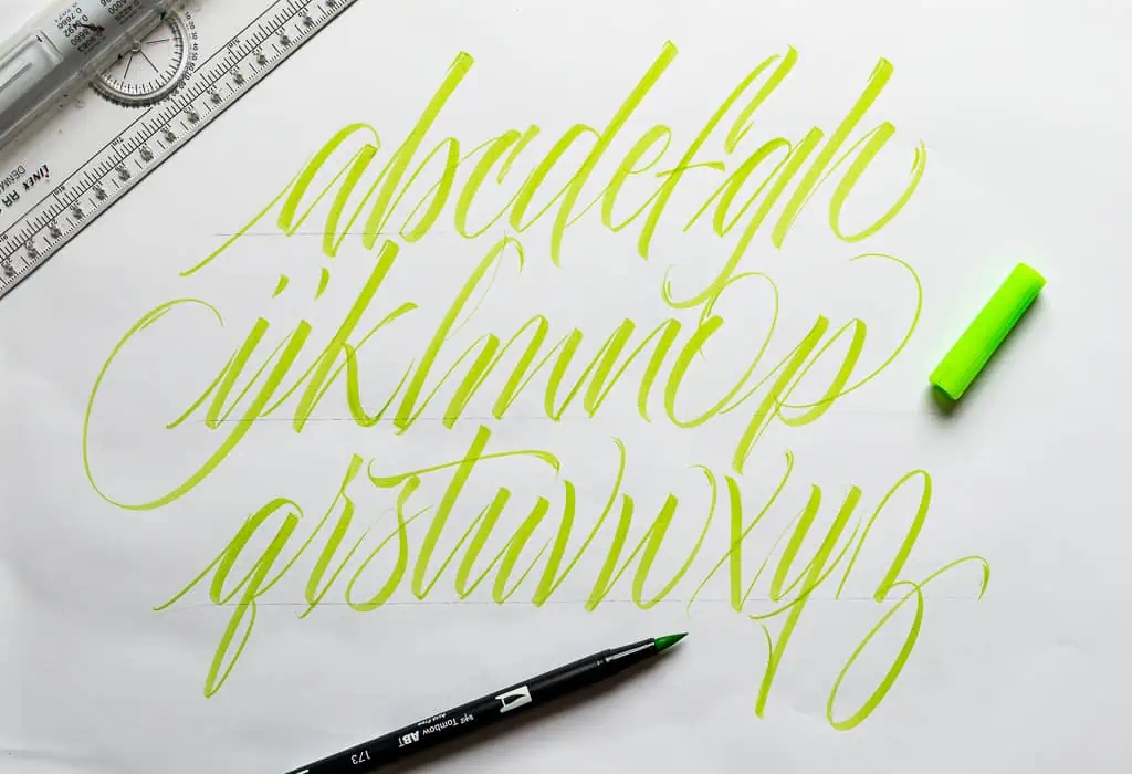 Custom yellow freestyle brush calligraphy alphabet on white paper. 