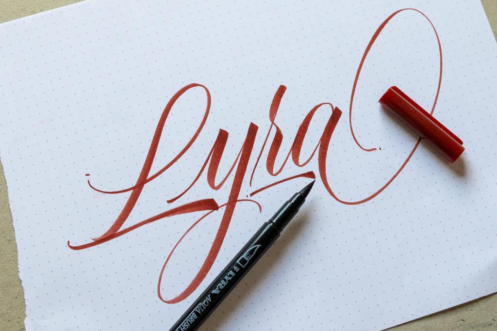 Maroon brush calligraphy on paper with Lyra brush pen